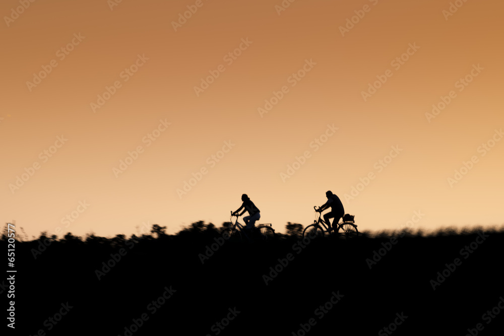 Silhouette of two riding bikers on sunset.