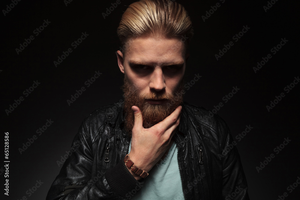 young man caressing his beard young man caressing his beard