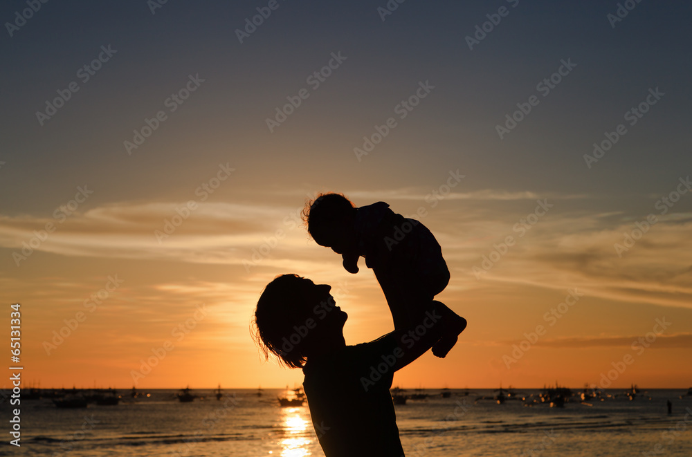 father and daughter silhuettes on sunset beach