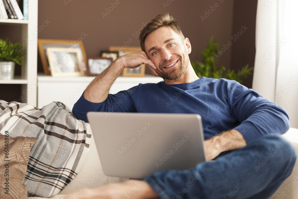 Portrait of smiling man with laptop on sofa Portrait of smiling man with laptop on sofa