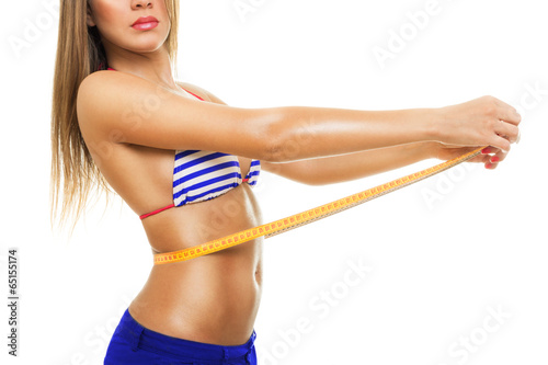 Fit young woman measuring her waist wearing bikini