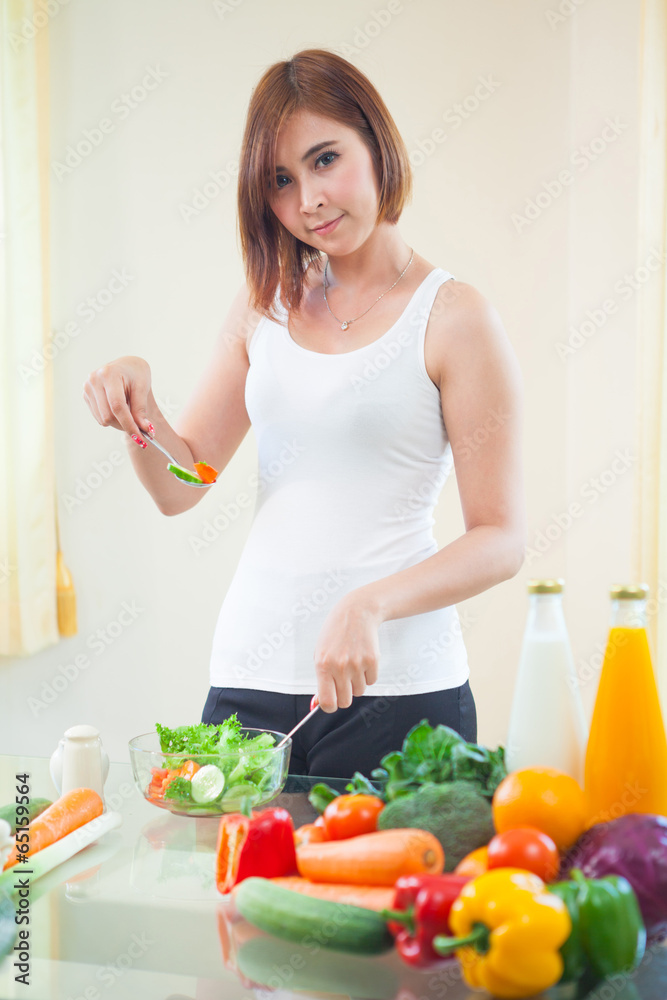 Happy woman cooking vegetables green salad
