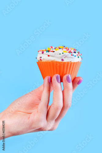 Hand holding cupcake on blue background