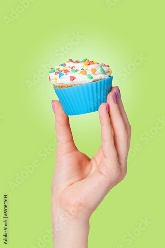 Hand holding cupcake on green background