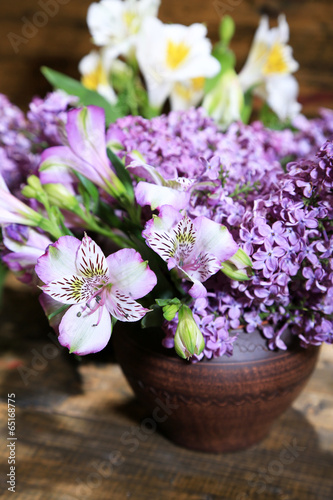 Beautiful spring flowers in pot on wooden background