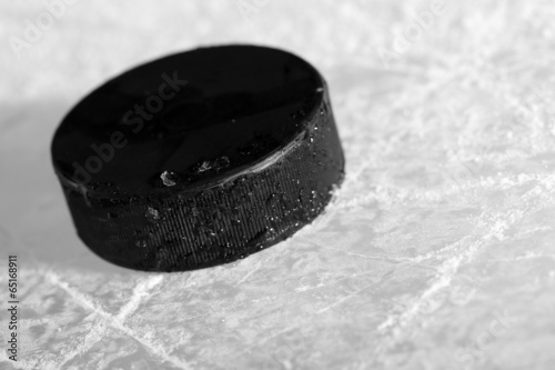 Black hockey puck on ice rink background