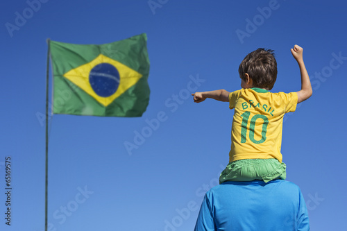 Boy and his father looking up at the Brazilian flag