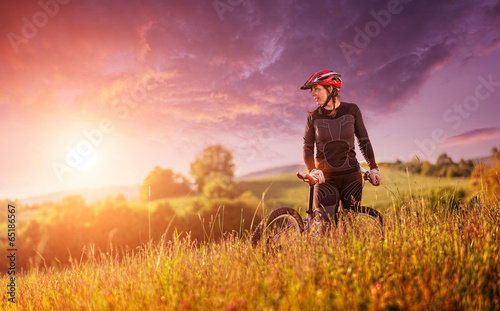 Sport bike woman relaxing on a meadow, beautiful landscape © Zsolnai Gergely