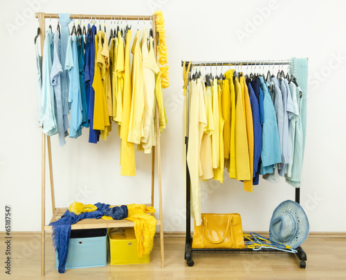 Color coordinated yellow and blue clothes on hangers.
