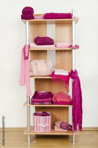 Tidy wardrobe with pink clothes nicely arranged on a shelf.