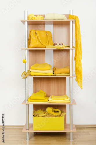 Tidy wardrobe with yellow clothes nicely arranged on a shelf.