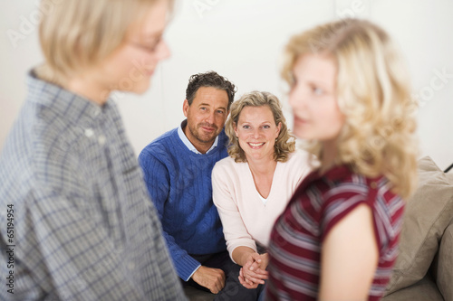 Teenager-Paar,den Eltern im Hintergrund sitzen