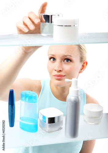 Kobieta, klientka stoi przy półce sklepowej i wybiera kosmetyki