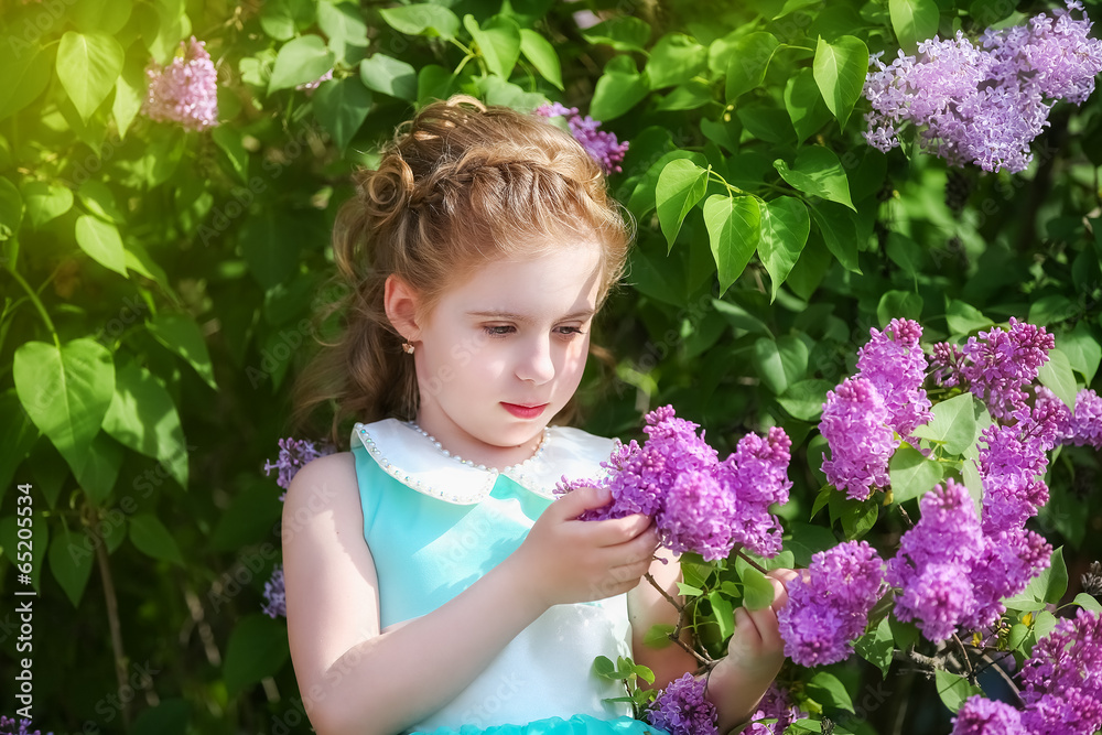 Fototapeta premium Beautiful little girl in a blue dress with a large white bow in