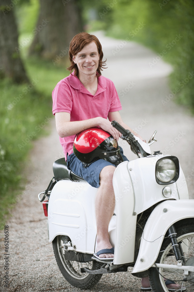Deutschland,Bayern,Junger Mann auf Moped,lächelnd,Porträt