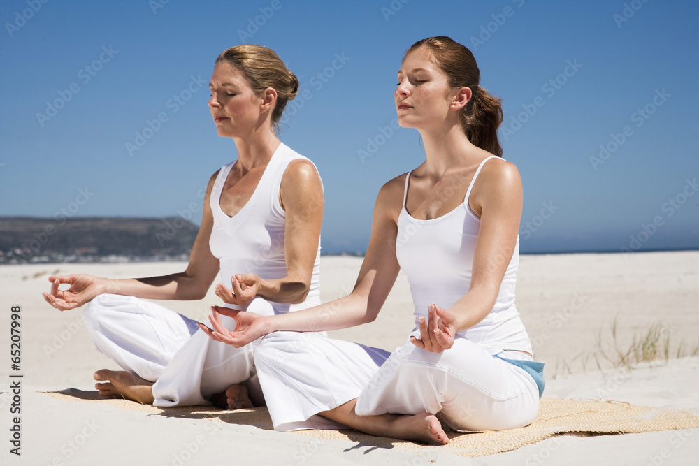 Zwei Frauen,die Ausübung von Yoga am Strand