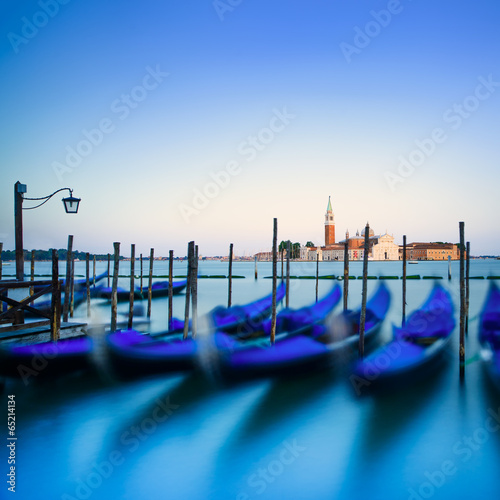 Venice, gondolas or gondole on sunset and church on background.