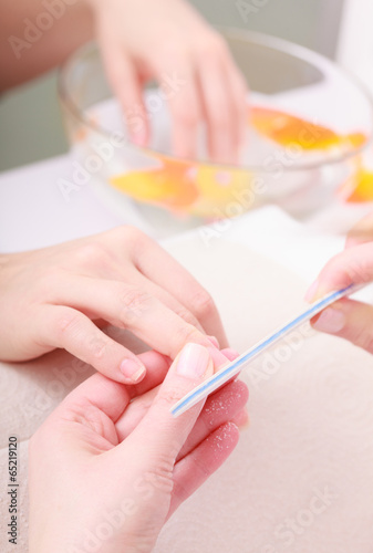 Beautician filing nails female client. Woman spa beauty salon