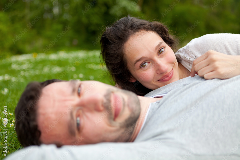 Attractive couple lying in grass at the park Attractive couple lying in grass at the park
