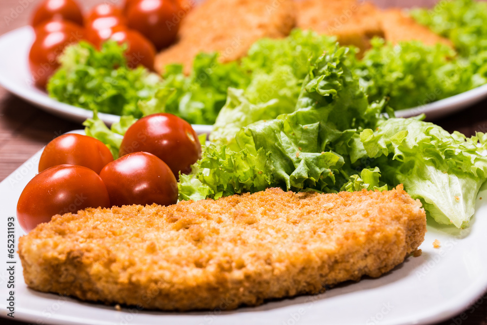 Fried battered chicken breast fillet  with lettuce on the plate