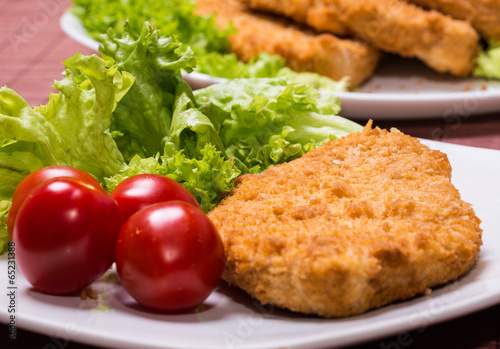Fried battered chicken breast fillet  with lettuce on the plate