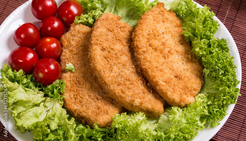 Fried battered chicken breast fillet  with lettuce on the plate photo
