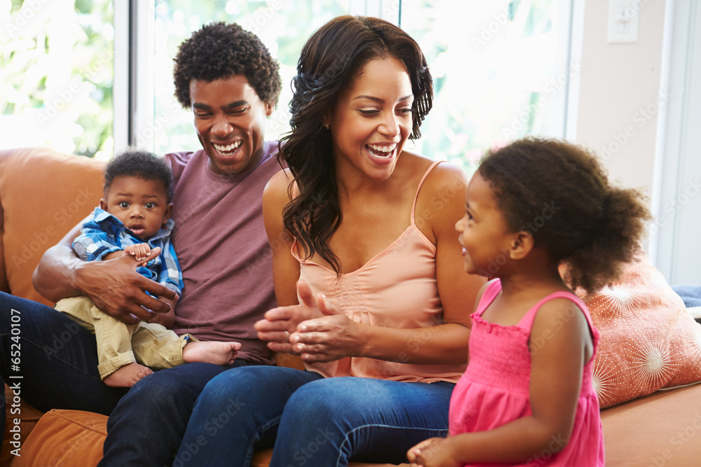 Young Family Relaxing On Sofa Together