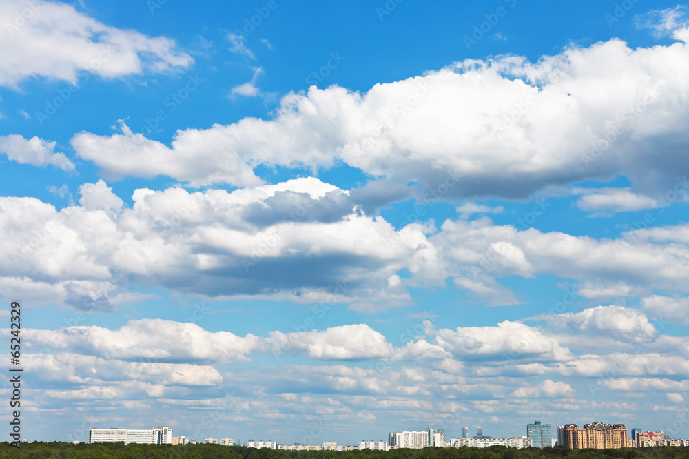 cityscape with white fluffy clouds in blue sky