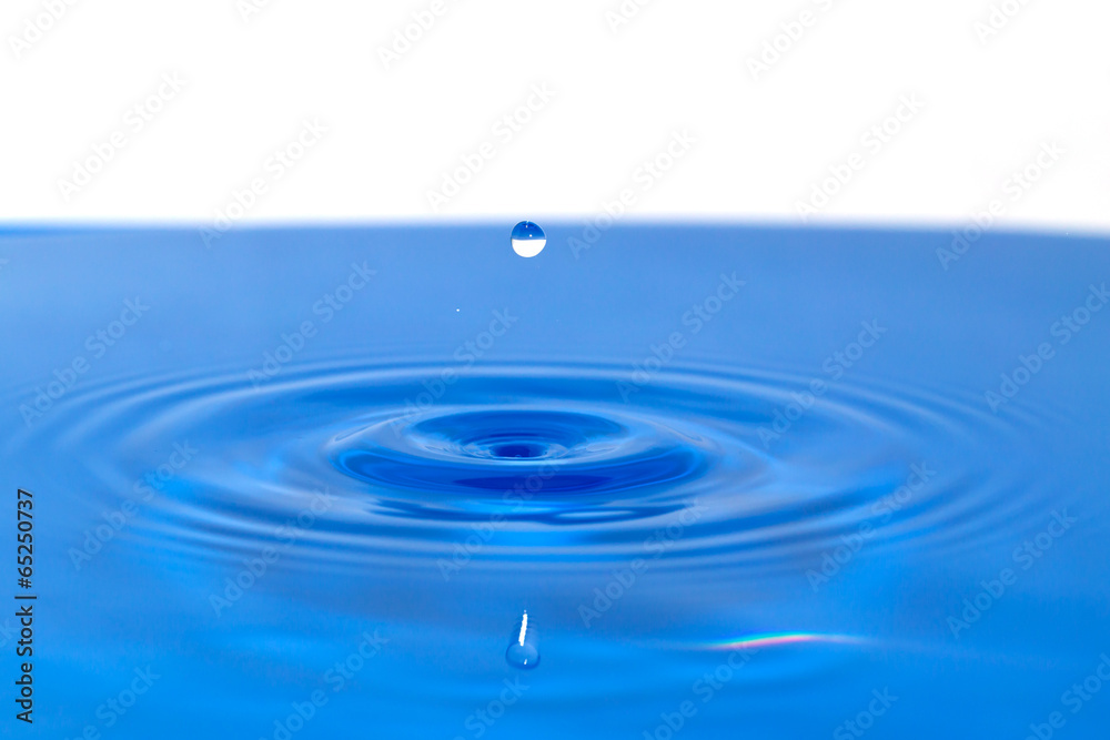 a drop of water falling in blue water. macro a drop of water falling in blue water. macro