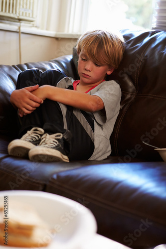 Unhappy Boy Sitting On Sofa At Home
