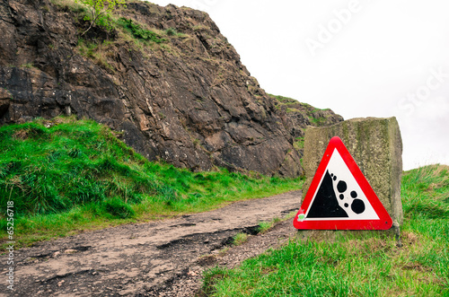 Red warning sign for falling rocks on a hill path in Edinburgh