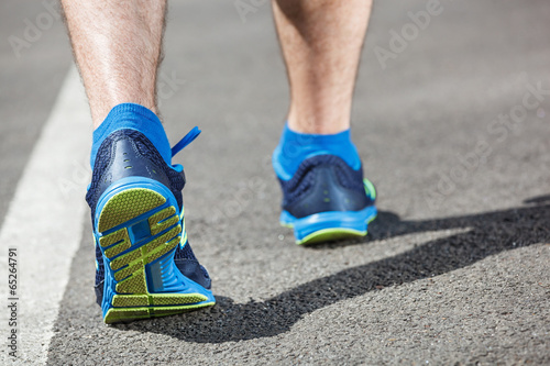 Runner feet running on stadium closeup on shoe.