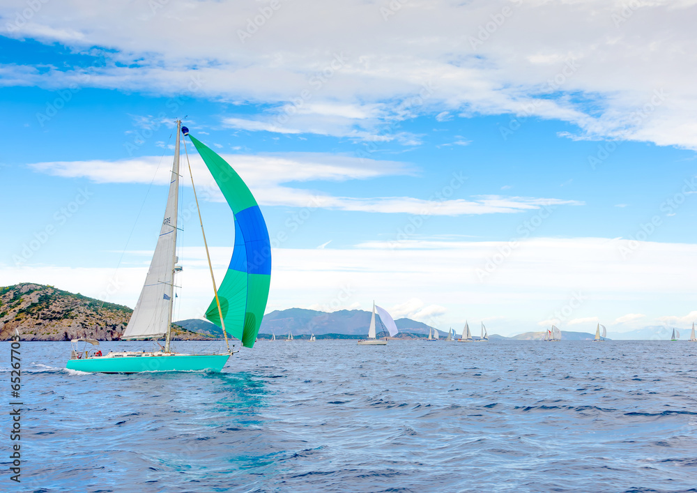 Naklejka premium Sailing boat with a green blue spinnaker out of Poros in Greece