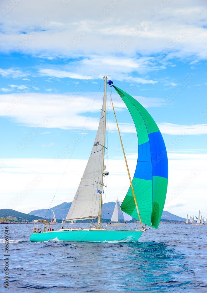 Naklejka premium Sailing boat with a green blue spinnaker out of Poros in Greece