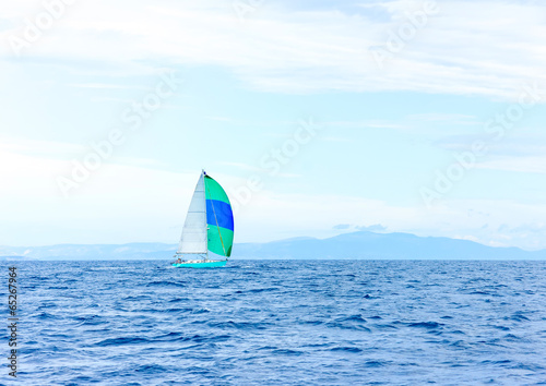 Sailing boat with a green blue spinnaker out of Poros in Greece