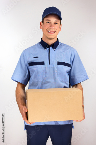 Handsome young delivery man carrying carton box