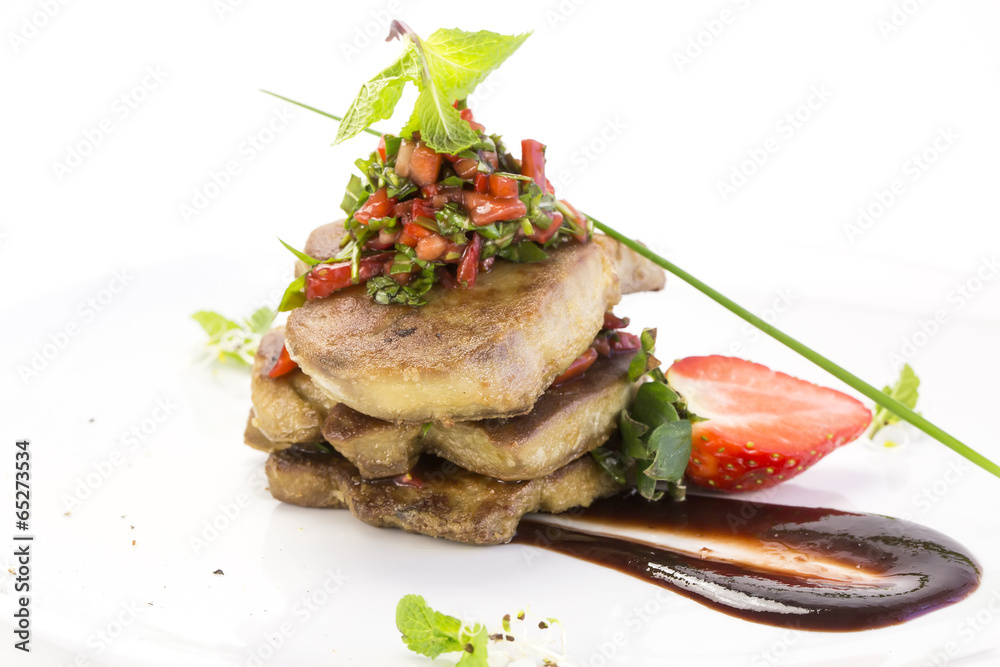 Roast goose liver is decorated with greens and strawberries