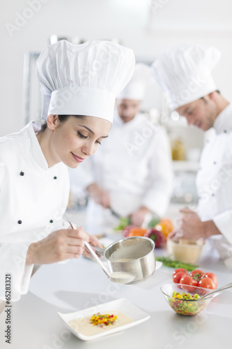  female chef preparing a dish her team in the background