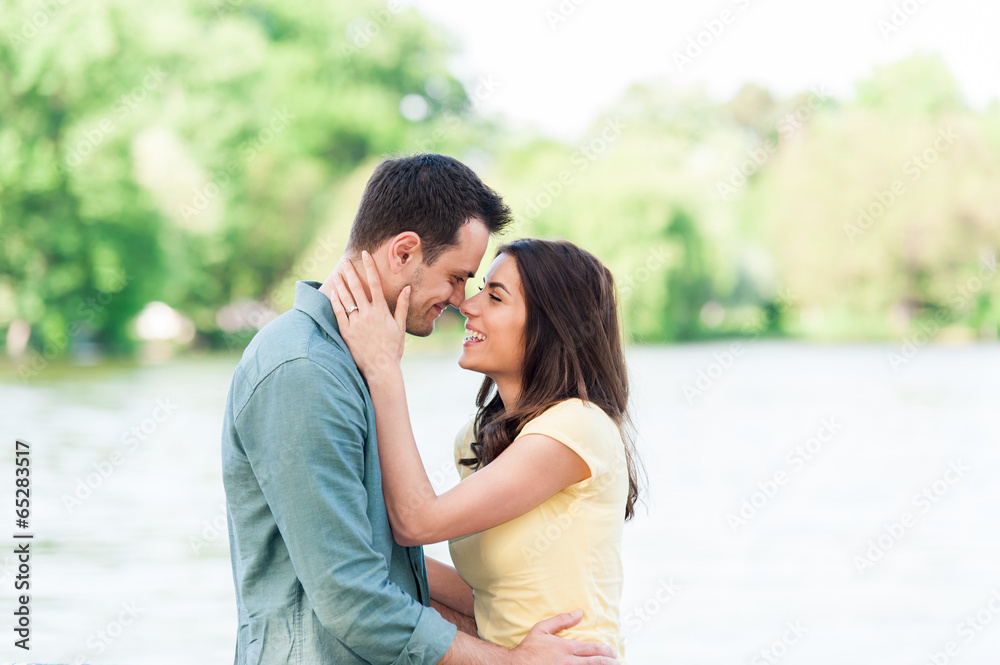 Young couple outdoors, near lake. hugging and havving a good time