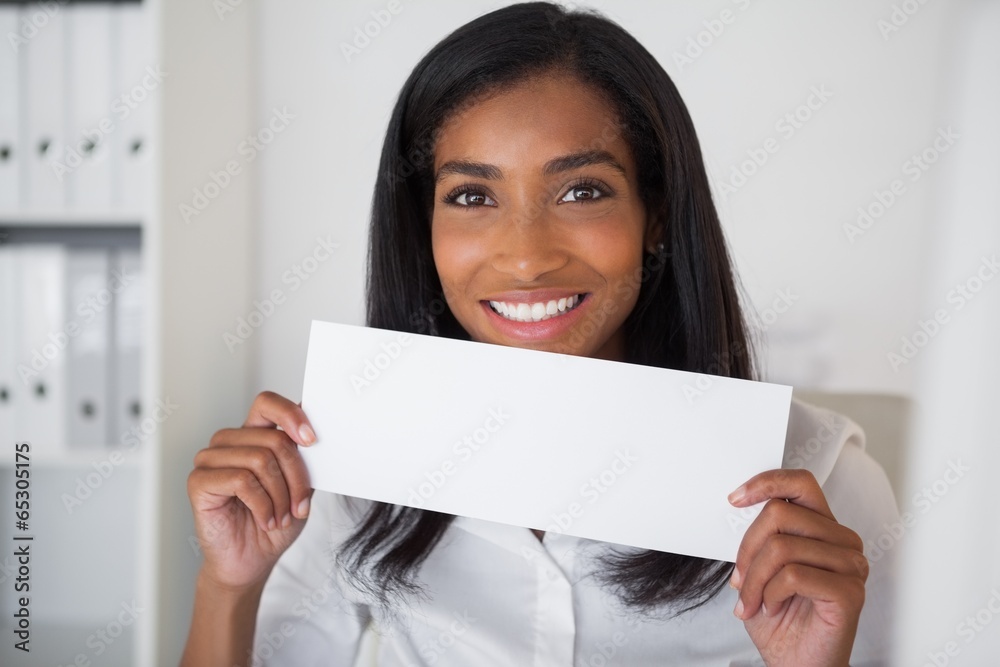 Pretty businesswoman showing white card at her desk Pretty businesswoman showing white card at her desk