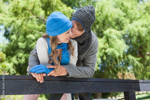 Cute couple standing in the park embracing by a fence