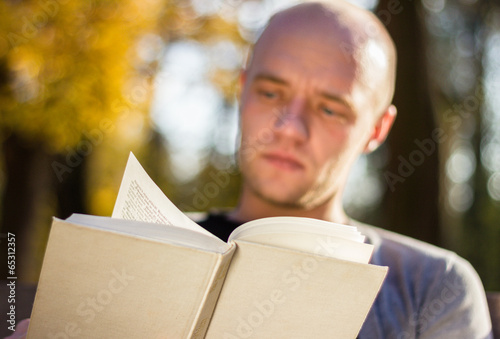 Young man relaxing in a park, reading a book