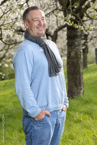 Friendly man in nature under blooming cherry tree