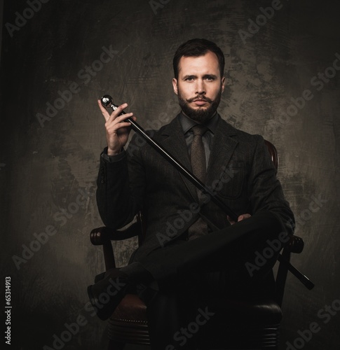 Handsome well-dressed with stick sitting in leather chair photo