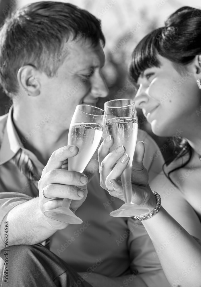 monochrome portrait of just married couple drinking champagne