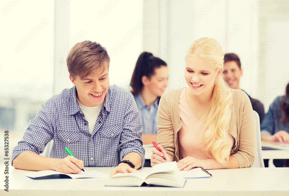 two teenagers with notebooks and book at school two teenagers with notebooks and book at school