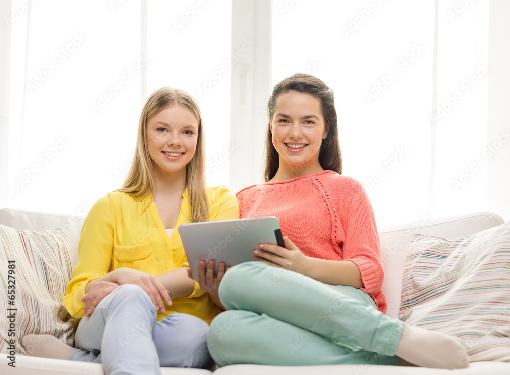 two smiling teenage girls with tablet pc at home