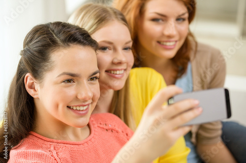 smiling teenage girls with smartphone at home