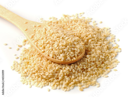 Wooden spoon with sesame seeds on a white background