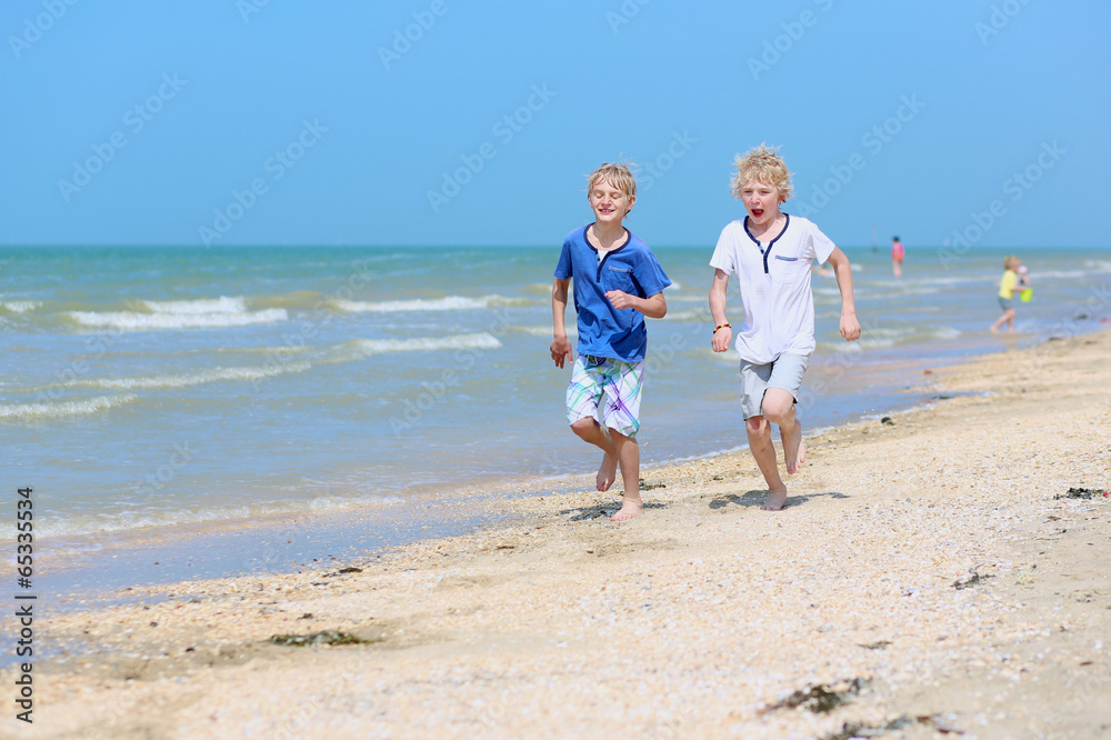 Two happy boys running on the beach